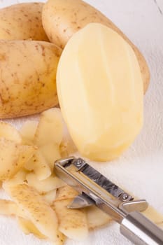Potatoes with peels and peeled with potato peeler Peeler as close-up