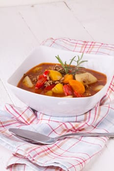 Bowl with stew goulash soup with potatoes and peppers as close-up