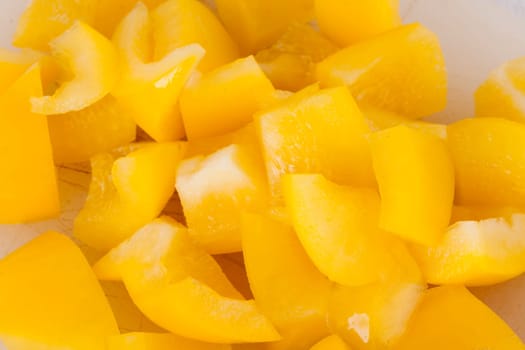 shaved yellow peppers in cubes on a rustic wooden board as a close-up