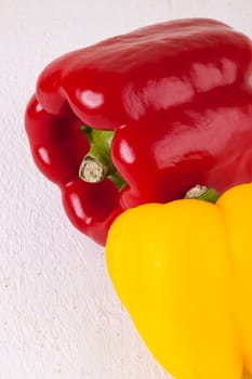 Fresh red and yellow peppers on a white wooden board as a close-up