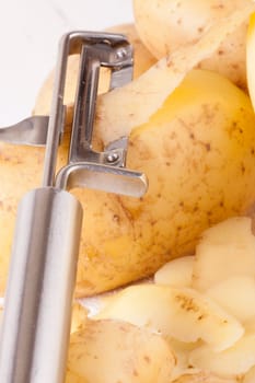 Potatoes with peels and peeled with potato peeler Peeler as close-up