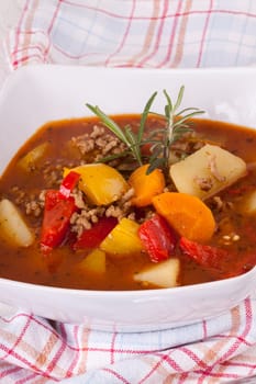 Bowl with stew goulash soup with potatoes and peppers as close-up
