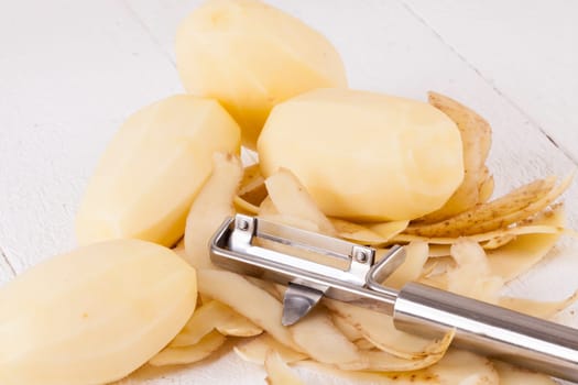 Potatoes with peels and peeled with potato peeler Peeler as close-up