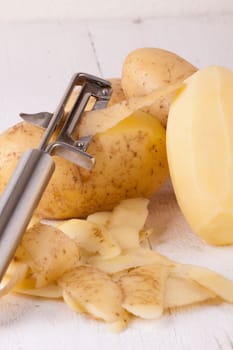 Potatoes with peels and peeled with potato peeler Peeler as close-up