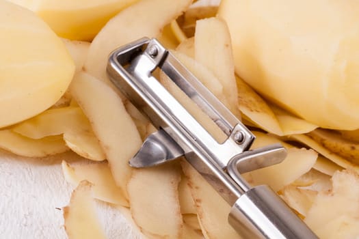 Potatoes with peels and peeled with potato peeler Peeler as close-up