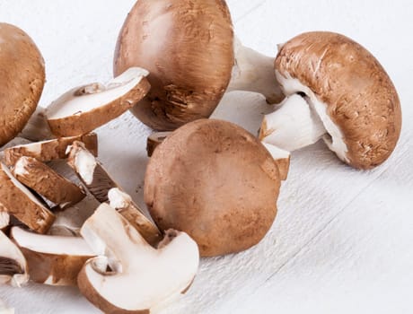 Fresh stone mushrooms Champiggnons whole and sliced on a white wooden board