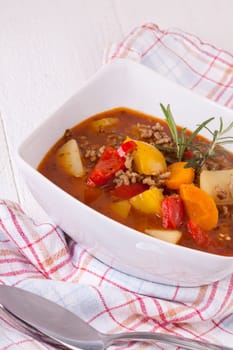 Bowl with stew goulash soup with potatoes and peppers as close-up