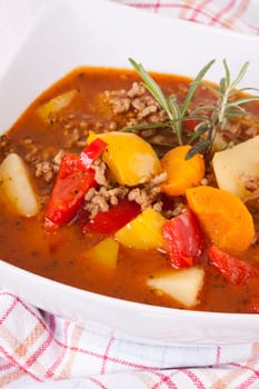 Bowl with stew goulash soup with potatoes and peppers as close-up