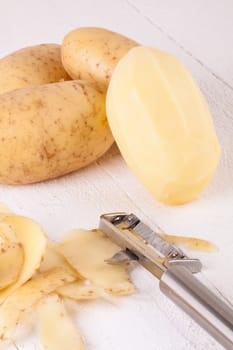 Potatoes with peels and peeled with potato peeler Peeler as close-up