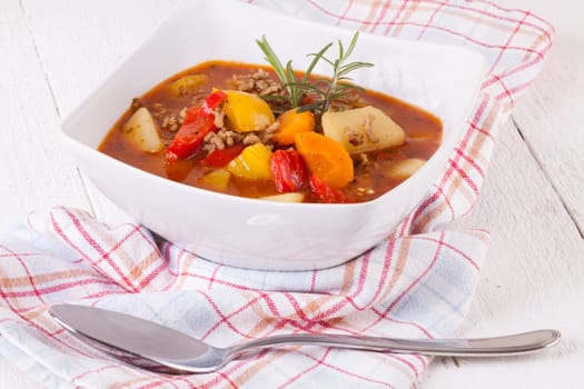 Bowl with stew goulash soup with potatoes and peppers as close-up