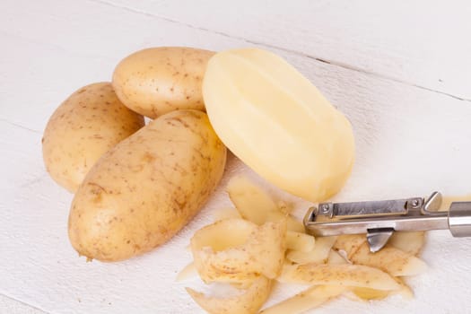 Potatoes with peels and peeled with potato peeler Peeler as close-up