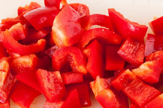 shaved red peppers in cubes on a rustic wooden board as a close-up