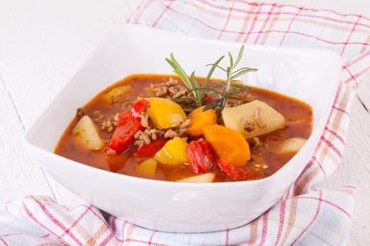 Bowl with stew goulash soup with potatoes and peppers as close-up