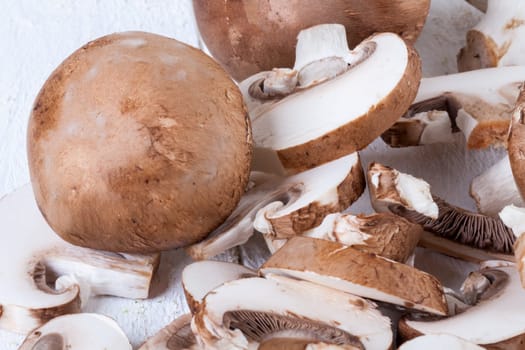 Fresh stone mushrooms Champiggnons whole and sliced on a white wooden board