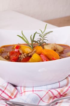 Bowl with stew goulash soup with potatoes and peppers as close-up