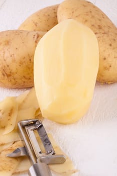 Potatoes with peels and peeled with potato peeler Peeler as close-up
