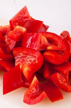 shaved red peppers in cubes on a rustic wooden board as a close-up
