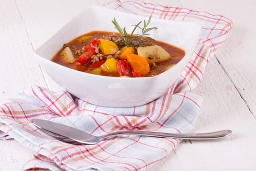 Bowl with stew goulash soup with potatoes and peppers as close-up