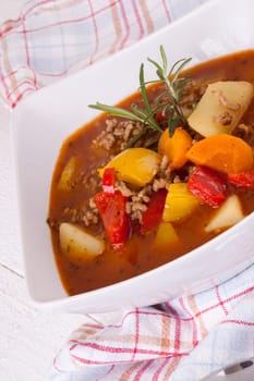 Bowl with stew goulash soup with potatoes and peppers as close-up