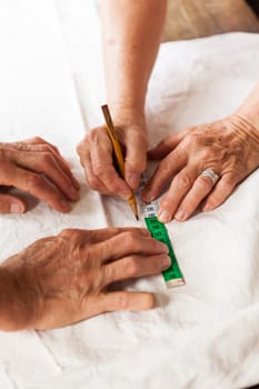 Hands with measuring tape scissors and pen when measuring fabric for the tailoring textile as a close-up