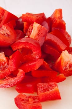 shaved red peppers in cubes on a rustic wooden board as a close-up