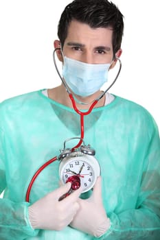 Doctor listening to an alarm clock's heartbeat