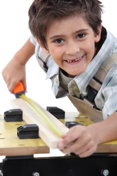 Young boy measuring a piece of wood to cut