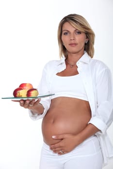 Pregnant woman holding a plate of apples