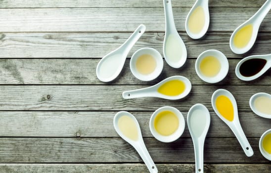 Topview of several soup spoons and sauce dishes filled with different colored oils