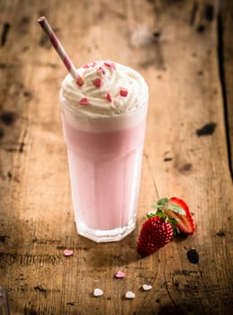 Berry smoothie or milkshake in a tall glass made from a blend of fresh strawberries and raspberries with frozen yoghurt or ice cream for a refreshing summer beverage