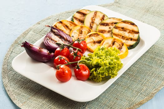 Serving of delicious roasted and fresh vegetables with courgette, zucchini, red onion, cherry tomato and lettuce for a tasty vegetarian snack