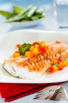 Grilled fish fillet served with colorful diced sweet peppers for a delicious seafood lunch