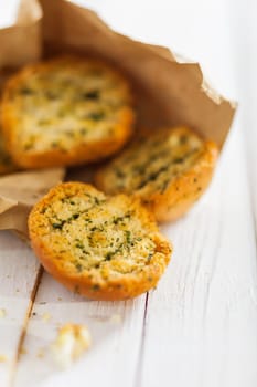 Crisp crunchy golden toasted or grilled herb buns or slices of baguette fresh from the BBQ in a rustic brown paper packet on a white picnic table