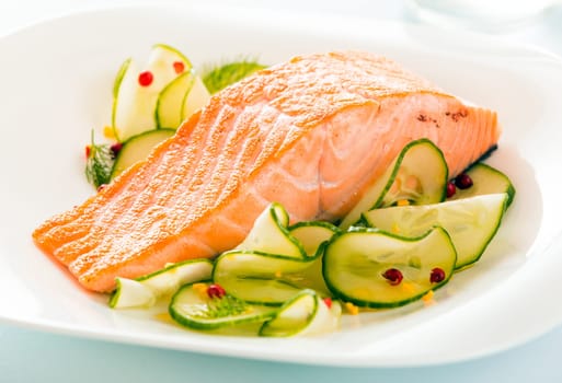 Gourmet oven-baked pink salmon steak served with thinly sliced cucumber as a delicious seafood starter to a dinner