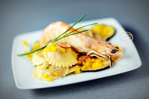 Seafood ravioli appetizer with shrimp or pink prawn and roasted eggplant slices for speciality Italian cuisine