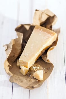 Wedge of luxury Parmigiano-Reggiano Italian cheese exclusive to certain provinces of Italy in a brown paper wrapper ready to be used as an ingredient in Italian cuisine