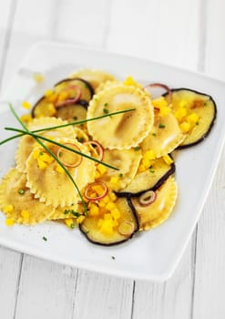 A serving of traditional Italian girasole ravioli served with roasted aubergine or eggplant garnished with chives