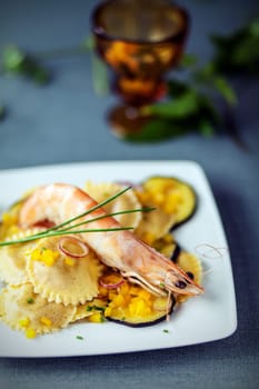 Seafood starter with prawns, Italian ravioli pasta and roasted slices of aubergine or eggplant garnished with fresh chives
