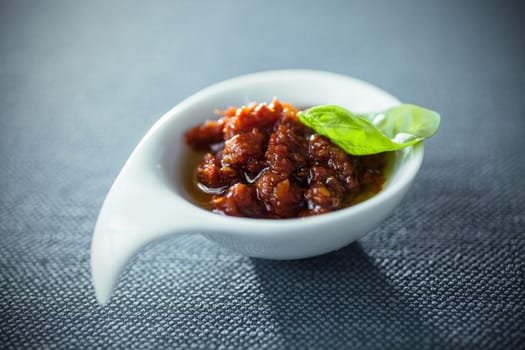 Spicy savory dip or chutney with tomatoes and chili in a modern stylish bowl garnished with fresh basil