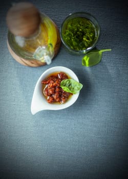 Savory condiments in a restaurant with a spicy dip, virgen olive oil in a decanter and fresh basil pesto, overhead view with copyspace