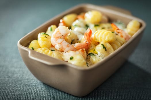 Bowl of tasty grilled prawns served with an aromatic sauce and fresh herbs in Italian gnocchi pasta for traditional Italian and Mediterranean cuisine