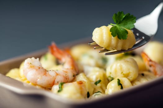 Italian gnocchi pasta, or dumplings made with semolina, with prawns or shrimps for a delicious seafood cuisine with one dumpling on a fork with selective focus