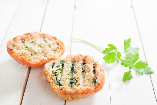 Delicious grilled golden crisp herb bread with fresh parsley on a white wooden garden table, low angle view