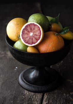 Delicious halved blood orange showing the red pulp on a citrus fruit display in a fruit bowl on an old rustic wooden table