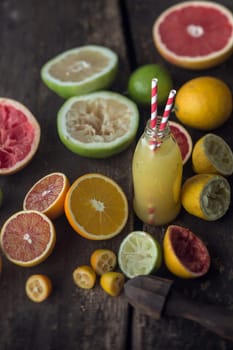 Preparing fresh grapefruit and lemon juice in a country kitchen with a freshly squeezed bottle of juice surrounded by halved grapefruit, lemons, oranges and limes