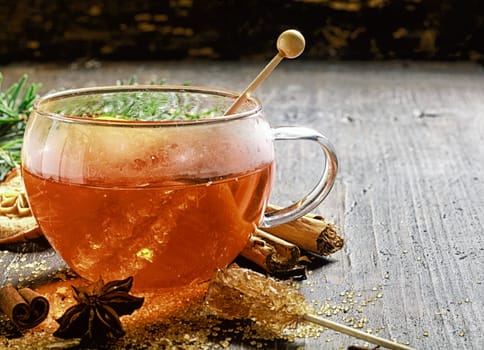 Cup of hot sweet spiced tea or gluhwein for celebrating the Christmas season surrounded by dried aromatic spices - cinammon and star anise - and caramelized sugar
