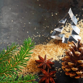 Christmas greeting card background with a cookie cutter in the shape of a Christmas tree with a pine branch, cone, caramelized brown sugar and star anise spice on a dark background with copyspace