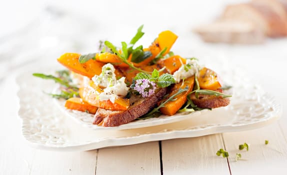 Gourmet Pumpkin Salad with Roasted Hokkaido and Grilled Bread. Served on White Wooden Table.