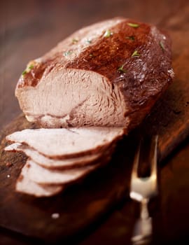 Carving roast meat for dinner with a tender lean portion of beef carved into thin slices ready for serving at table