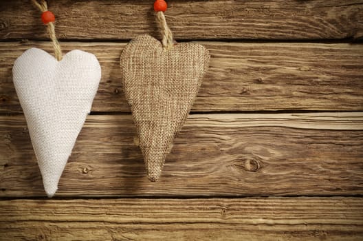 Christmas background for your sweetheart with two handmade rustic textile hearts in white and brown burlap on textured wooden boards with copyspace for your seasonal greeting